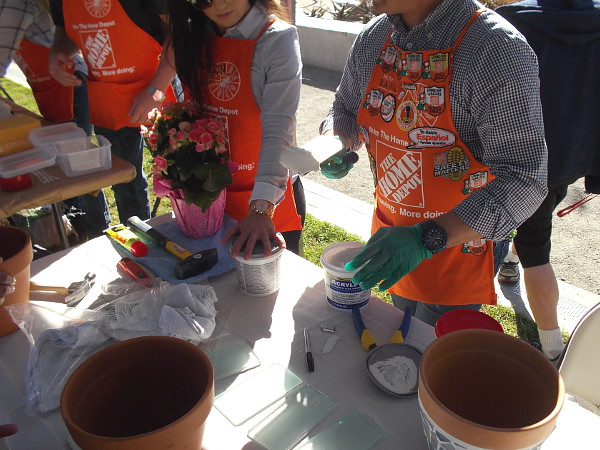 A layer of ceramic tile adhesive is applied to the exterior of clay pots.