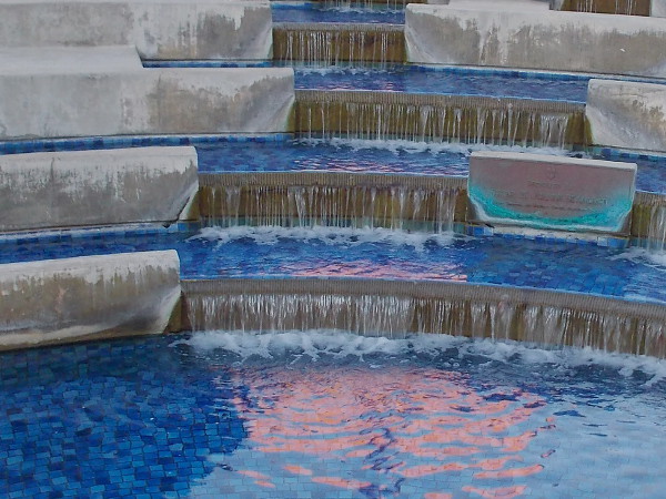 A reddish splash in blue water. The fountain in front of Scripps Mercy Hospital.