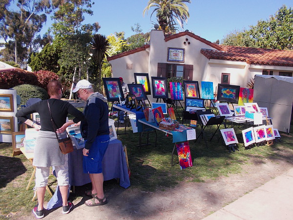 A couple peruses works by local artists out on display in Balboa Park.