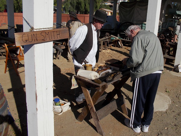 A gun smith who assembles his own old-fashioned rifles and firearms shows a visitor some examples in San DIego's historic Old Town.