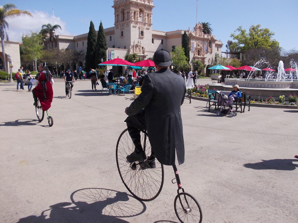 A pair of penny-farthing riders head through the Plaza de Panama in Balboa Park on a sunny San Diego day.