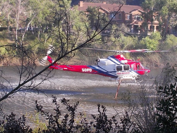 One of the San Diego Fire Department's two firefighting helicopters fills it water tank using a hose lowered into the San Diego River in Mission Valley.