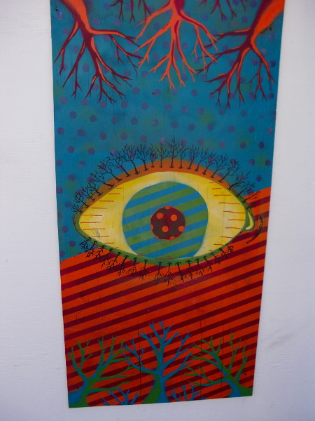 A psychedelic, tree-lined eyeball between colorful barren branches.