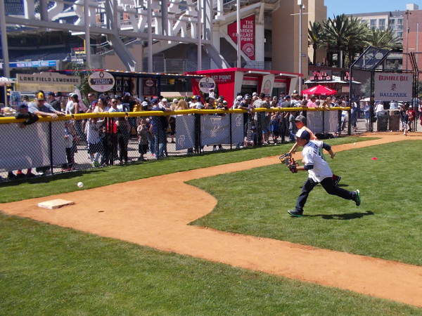 Kid infielders charge a batted wiffle ball at the miniature baseball field in Park at the Park.