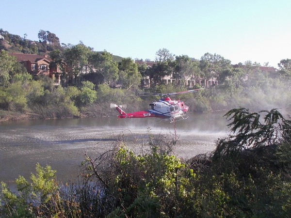 The long hose quickly sucks a good quantity of water from the river. The pilot is highly skilled, hovering the helicopter above the water, steady as a rock.