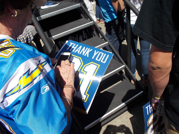 A fan in a Chargers team jersey holds a poster that says Thank You 21. That was LaDainian Tomlinson's number.