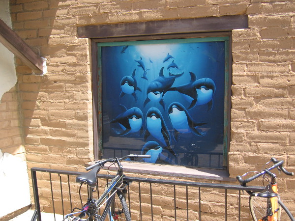 Fun marine artwork depicts a pod of dolphins in the ocean. A window of the Wyland Galleries in Seaport Village.