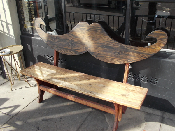 A bench shaped like a mustache. A fun sight in front of a barber shop.