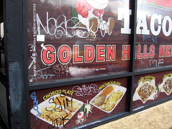 A Mexican taco shop and graffiti on the windows. The neighborhood today is a bit rundown, but sunny and pleasant.
