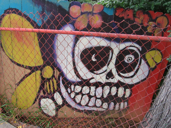 A wooden fence along the sidewalk contains amazing, colorful murals, beginning with this flowery skull.
