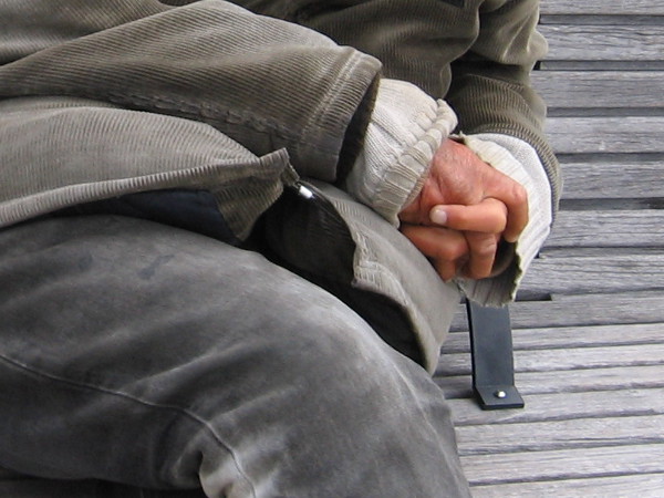 The weathered old hands of a sleeping homeless man.