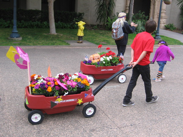 Towed by young people, floral displays head down Balboa Park's central El Prado.