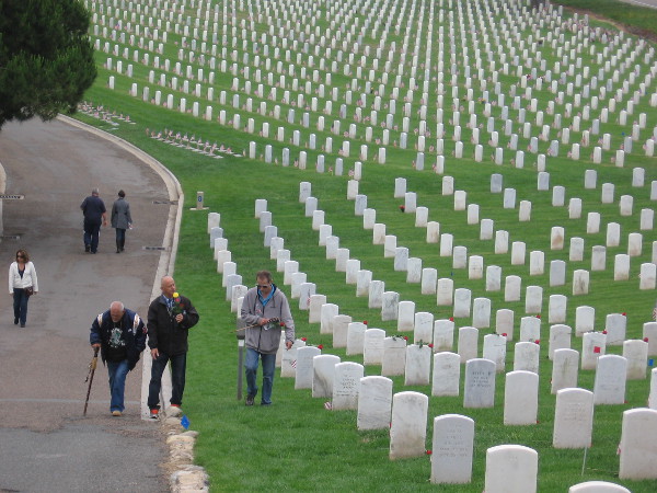 The living walk thoughtfully through Fort Rosecrans National Cemetery in San Diego.