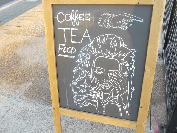 Funny sign on East Village sidewalk. Rubbing an eye to wake up. Maybe some coffee will help!