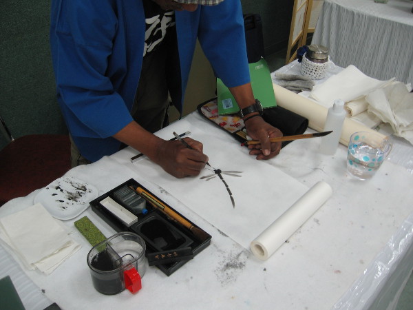 Gifted artist with a great laugh creates a beautiful dragonfly with ink. Demonstrations were part of this weekend's art show inside the Casa del Prado in Balboa Park.