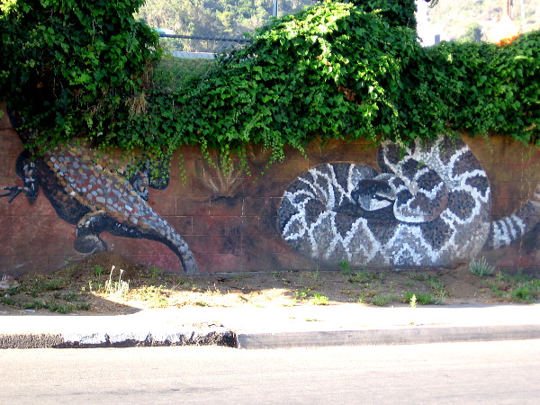 Some sort of lizard--perhaps a Gila monster--is half hidden by leaves, while a rattlesnake coils nearby!