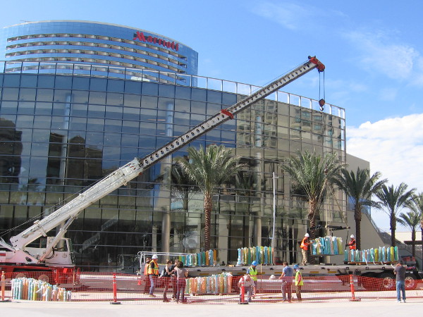 A big crane lifts sections of the artwork into position on a sunny Saturday morning in San Diego. The Marriott Marquis' brand new conference center shines in the background.