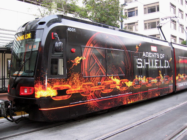 2016 San Diego Comic-Con will bring fans a new version of the familiar Agents of S.H.I.E.L.D. trolley wrap. This year, the design features a burning chain!