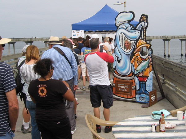 As we approach the hub of the anniversary event, just past the Walking on Water Cafe, a lady peers through the jaws of a shark!