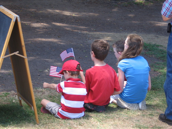 Kids listening to the speeches wave American flags.