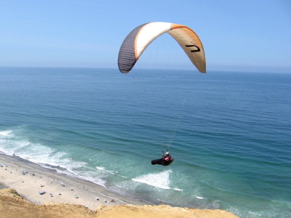 Paraglider high above the Pacific Ocean catches a warm summer updraft created by sandstone cliffs at San Diego's famous Torrey Pines Gliderport.