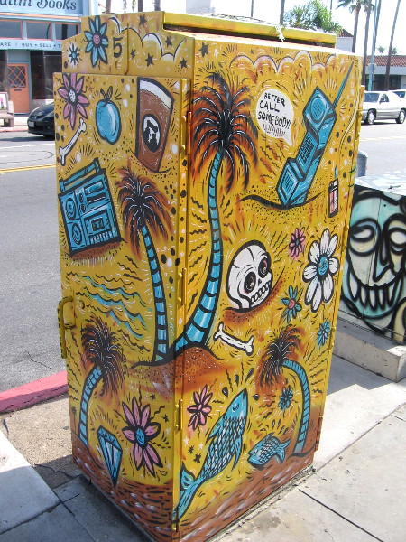 Utility box on 30th Street has tropical palm trees, flowers, fish and a skull.