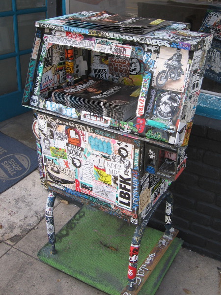 Newspaper box covered top to bottom with decals.