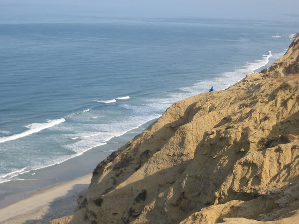 Looking north along the San Diego coast from a point above Black's Beach. A solitary figure looks out at the mighty ocean from atop a weathered sandstone cliff.