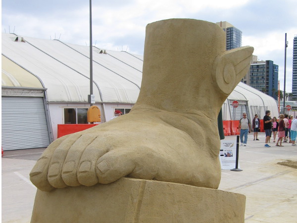 A large winged foot carved of sand appears ready to take flight.