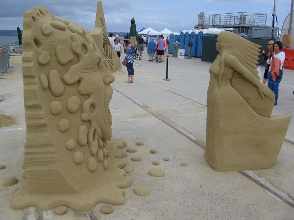 An angry face yells at a graceful woman made of sand.
