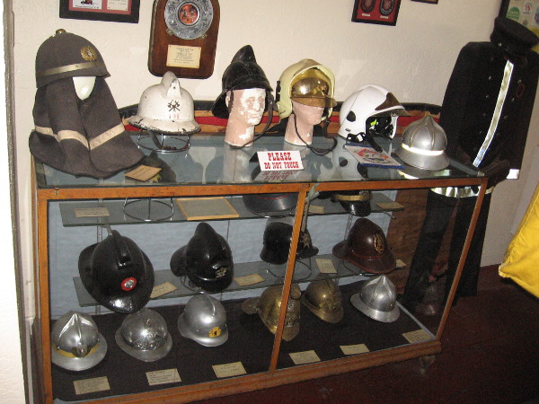 One glass display case in the museum contains all sorts of old fire fighter helmets and protective headgear.