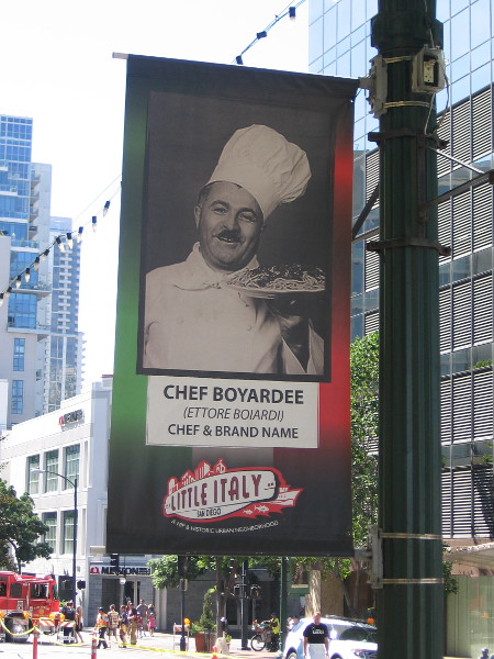 Chef Boyardee (Ettore Boiardi) appears on a street lamp banner in Little Italy.