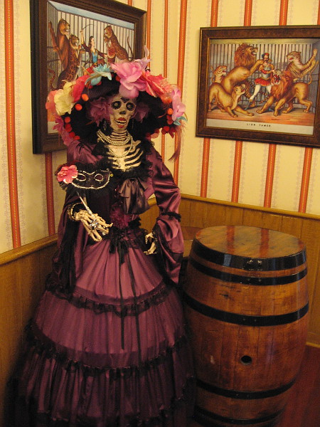 A shy skeleton in quite fancy attire stands silently in the corner of the Old West 1800s saloon.