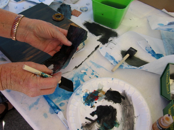 Applying some paint to a strip of material.