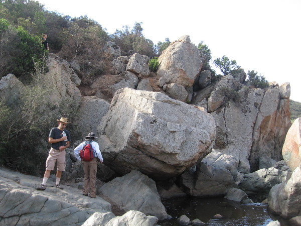 Hikers pause above a pool of water which is captured by large blocks of volcanic rock. When the creek crests, it can rise many feet and submerge this area.