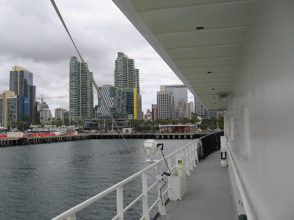 Heading forward along the ship's port side. Downtown San Diego buildings rise across the water.