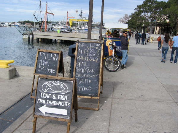 Sidewalk signs try to lure people out onto a pier near Seaport Village. Fresh seafood caught by local fishermen is sold here every Saturday morning.