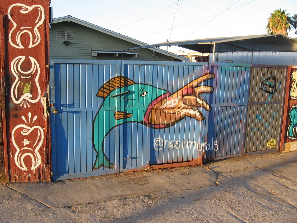 A hand emerges from the mouth of a fish at The Nest Murals.