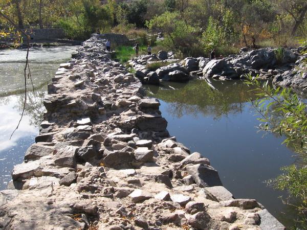 Standing on the north end of the Old Mission Dam. Materials used in constructing the dam include volcanic rock found in this area.