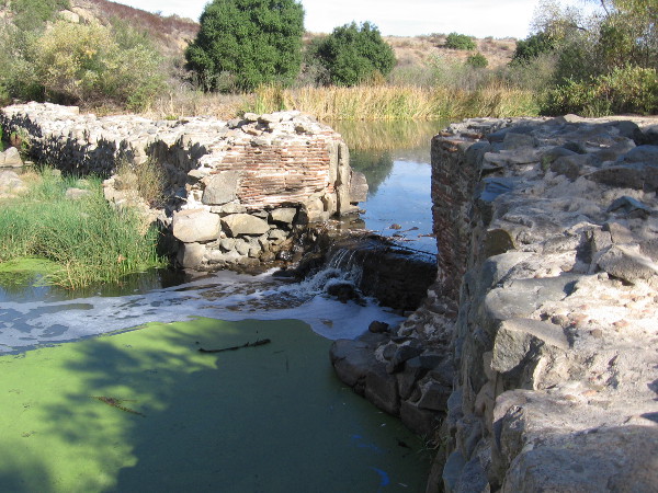 A vertical groove in the dam wall shows where the floodgate used to exist. The dam was completed around 1813, and the long flume to Mission San Diego was completed several years later.