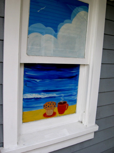 Beach, clouds, muffin and coffee in a window of the Seaport Cookie Company.