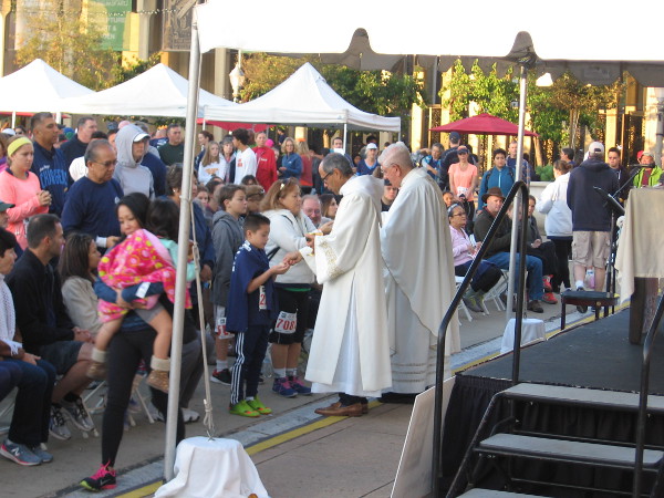Catholic priests perform a religious service in the Plaza de Panama for the faithful before the Thanksgiving race to help the homeless.
