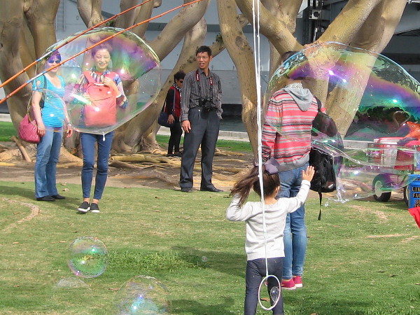Tourists on San Diego's Embarcadero have fun with gigantic bubbles.