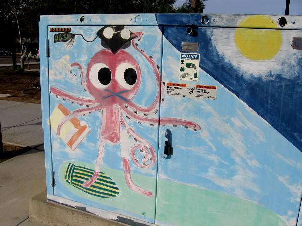 Across from the North Campus of UCSD, this octopus carrying a book and donning a graduation cap is riding a surfboard!