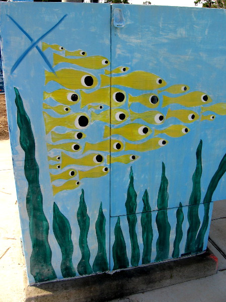 Another side of the big utility box has yellow fish forming a triangle as they swim above seaweed.