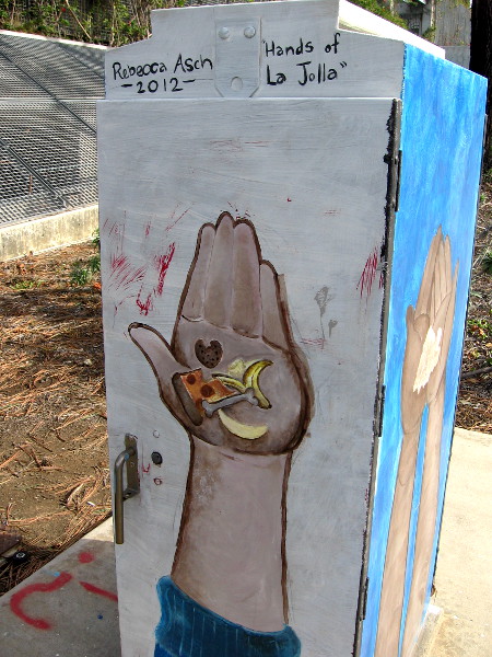 One side of a box near an entrance to UCSD. Hands of La Jolla by Rebecca Asch. It's holding food.