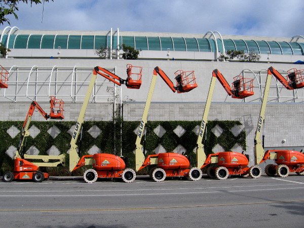 Engine powered articulating boom lifts in a row behind the San Diego Convention Center.