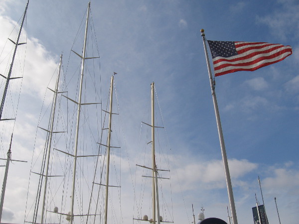 The high masts of super yachts rise behind the convention center into the sky.