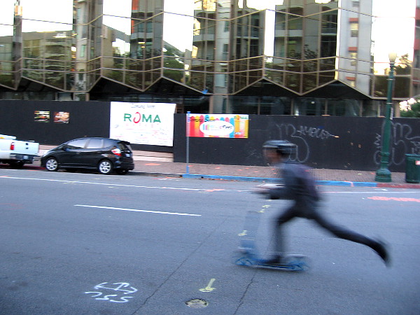 Young man in business suit rides a scooter to work early one morning in downtown San Diego.