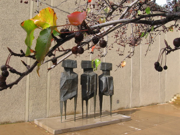 Dripping branches and leaves seem to overhang The Watchers. This outdoor sculpture is by artist Lynn Chadwick.